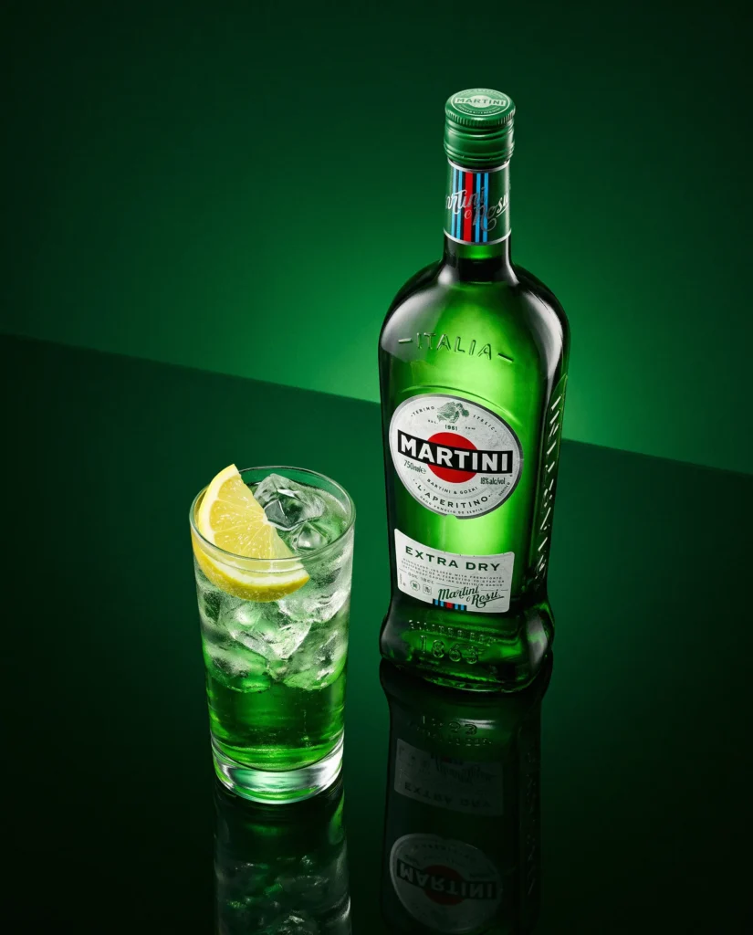 Green vermouth bottle and iced serve on a dark green sweep