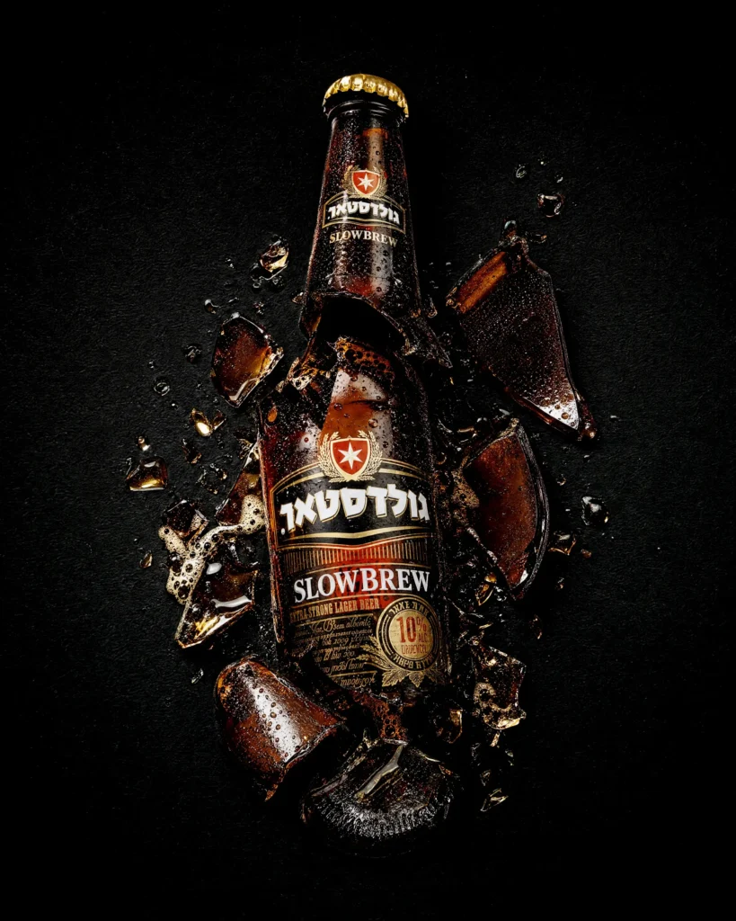 Beer bottle shattering with glass and liquid on black