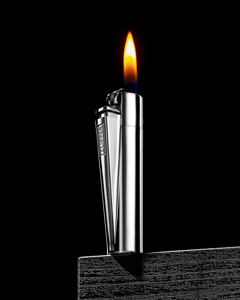 Chrome pocket lighter alight on a black wooden block