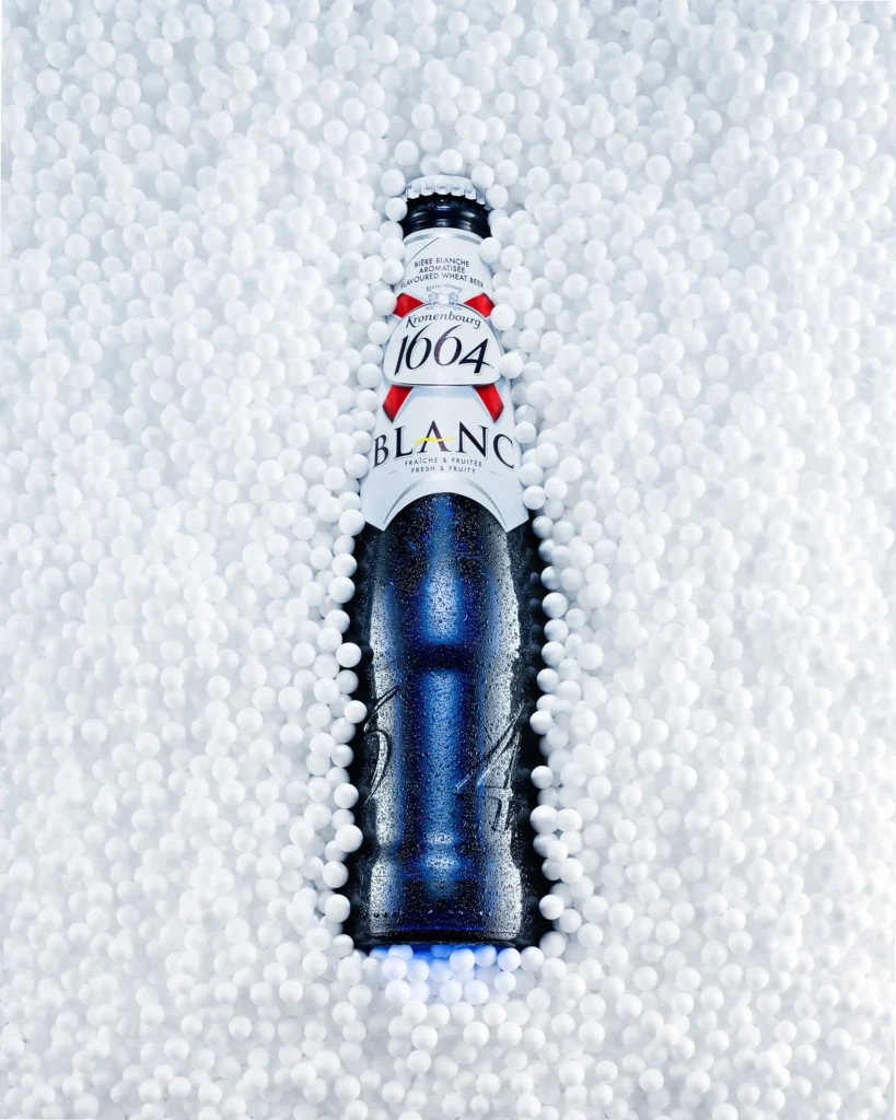 Blue beer bottle bedded in white polystyrene beads