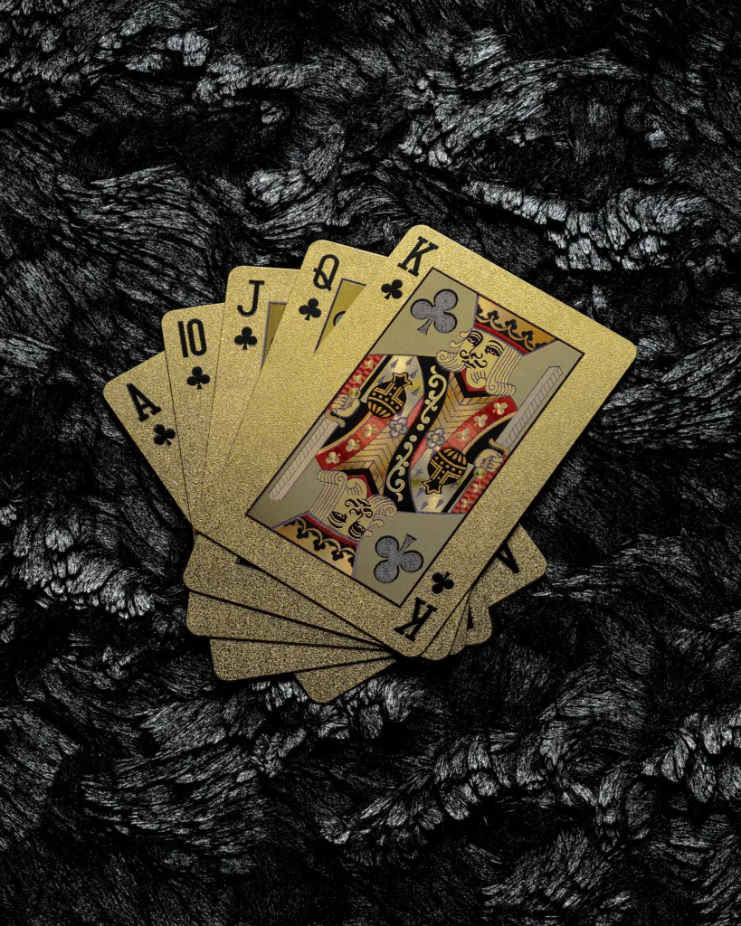 Gold-edged playing cards fanned on dark textured rock