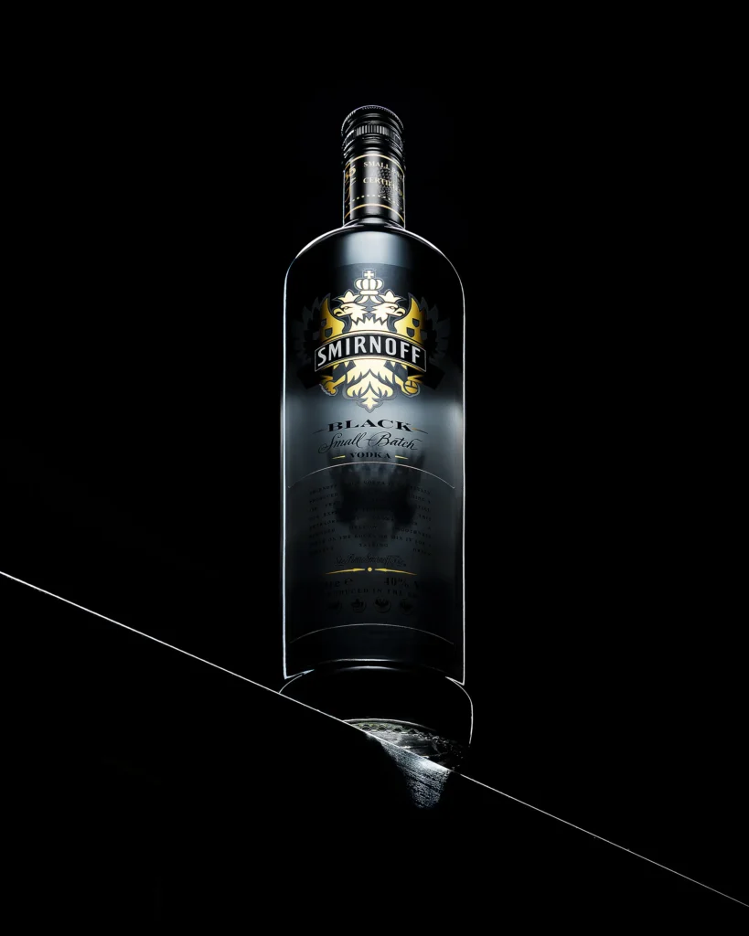 Dark spirits bottle above its own reflection on a black plane