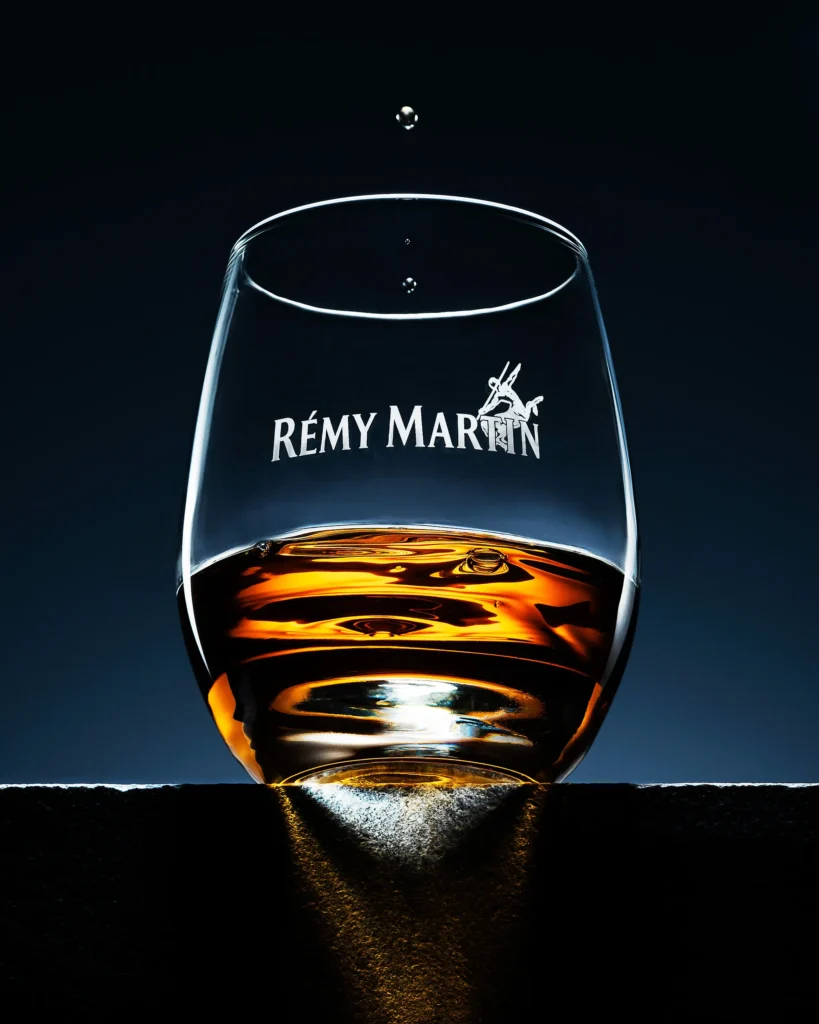Cognac resting in a stemless glass with a drop falling above it