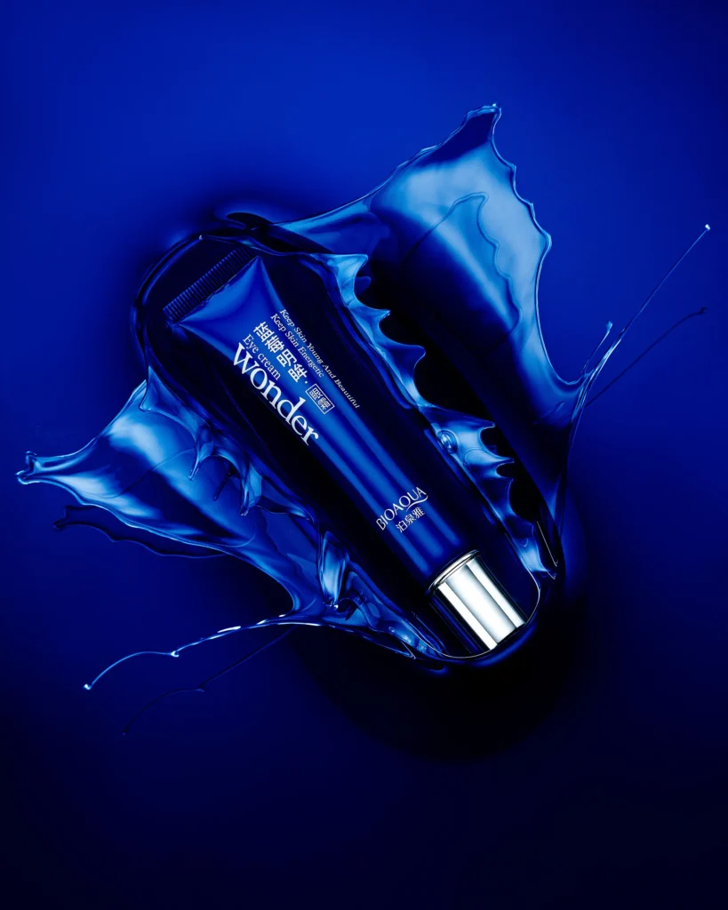 Blue skincare tube caught in a crown of blue liquid