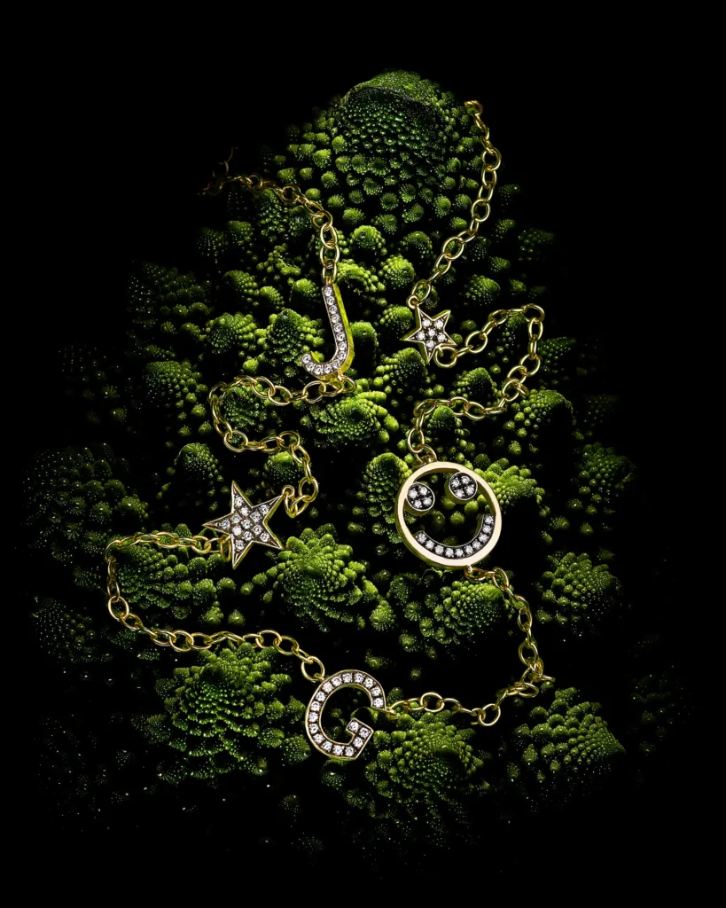 Gold and diamond chain jewellery laid over green romanesco florets