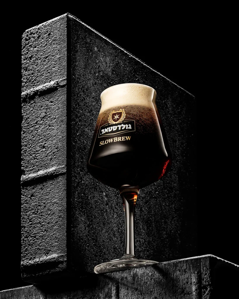 Dark beer in a stemmed glass against a black brick wall