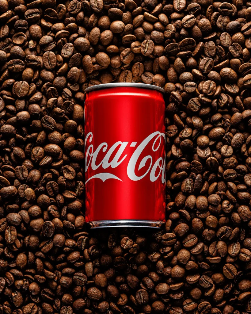 Red soft-drink can half-buried in roasted coffee beans