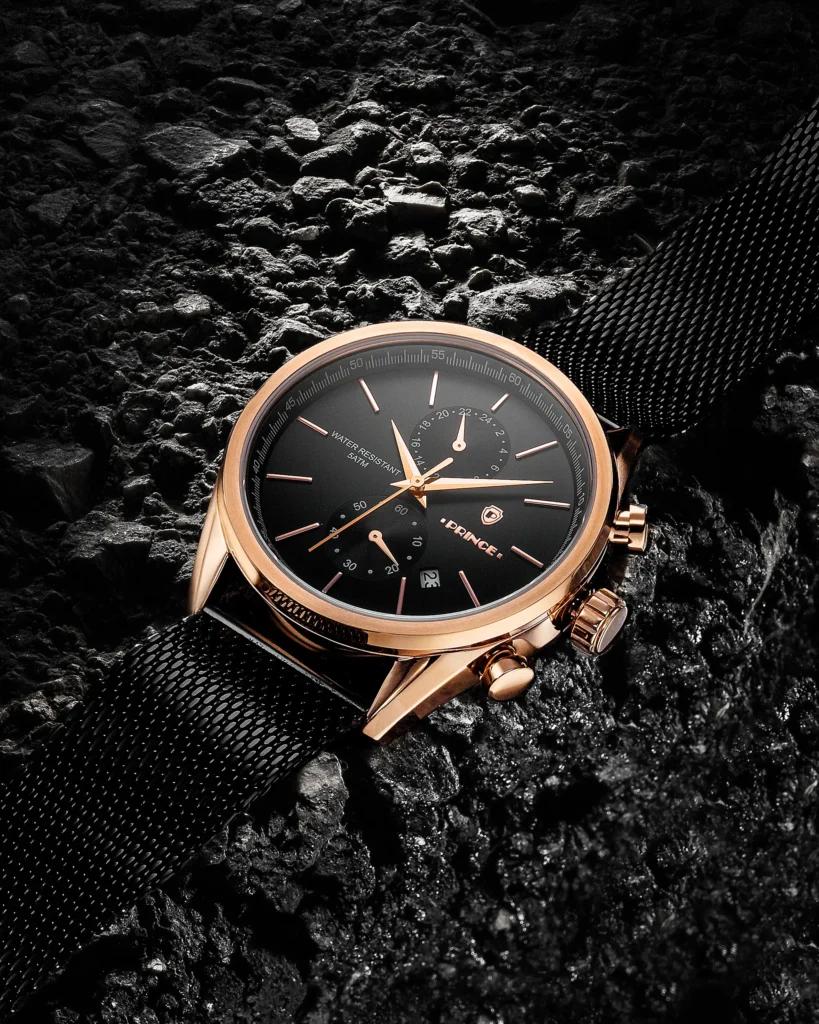 Rose-gold chronograph on black mesh over crushed coal