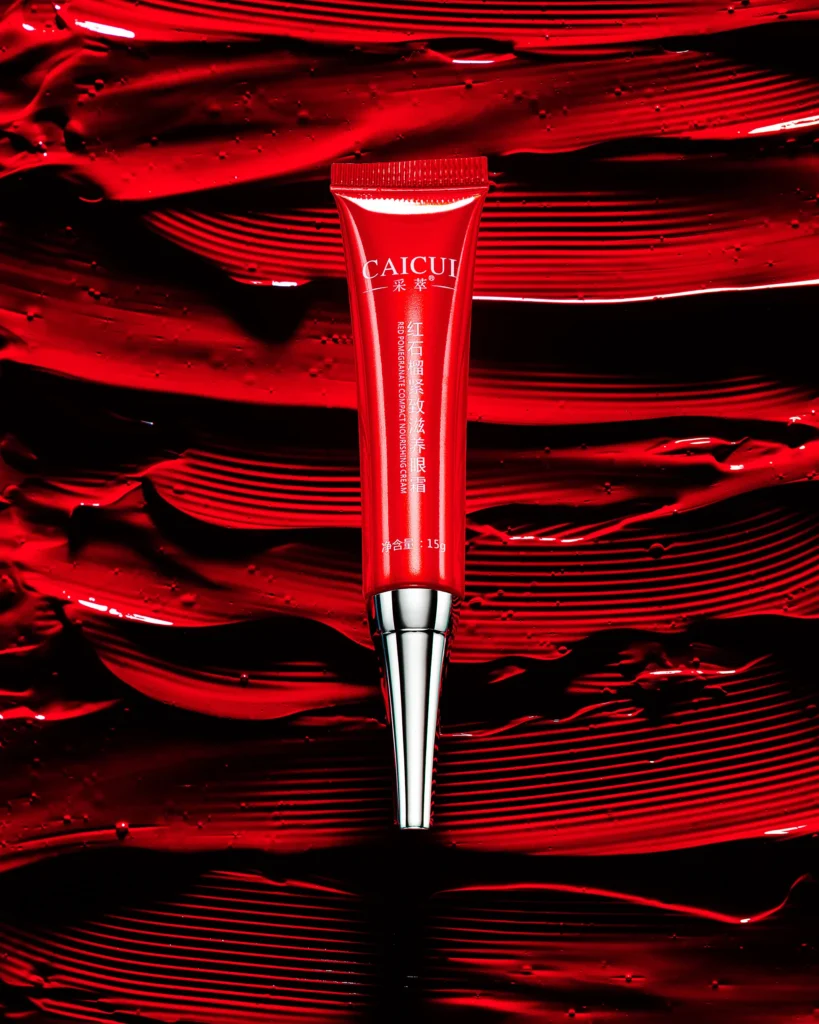Red cosmetic tube standing on thick red paint strokes