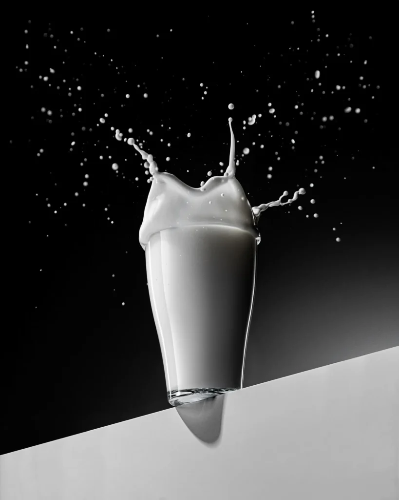 Milk splashing from a tumbler tipped on a white edge