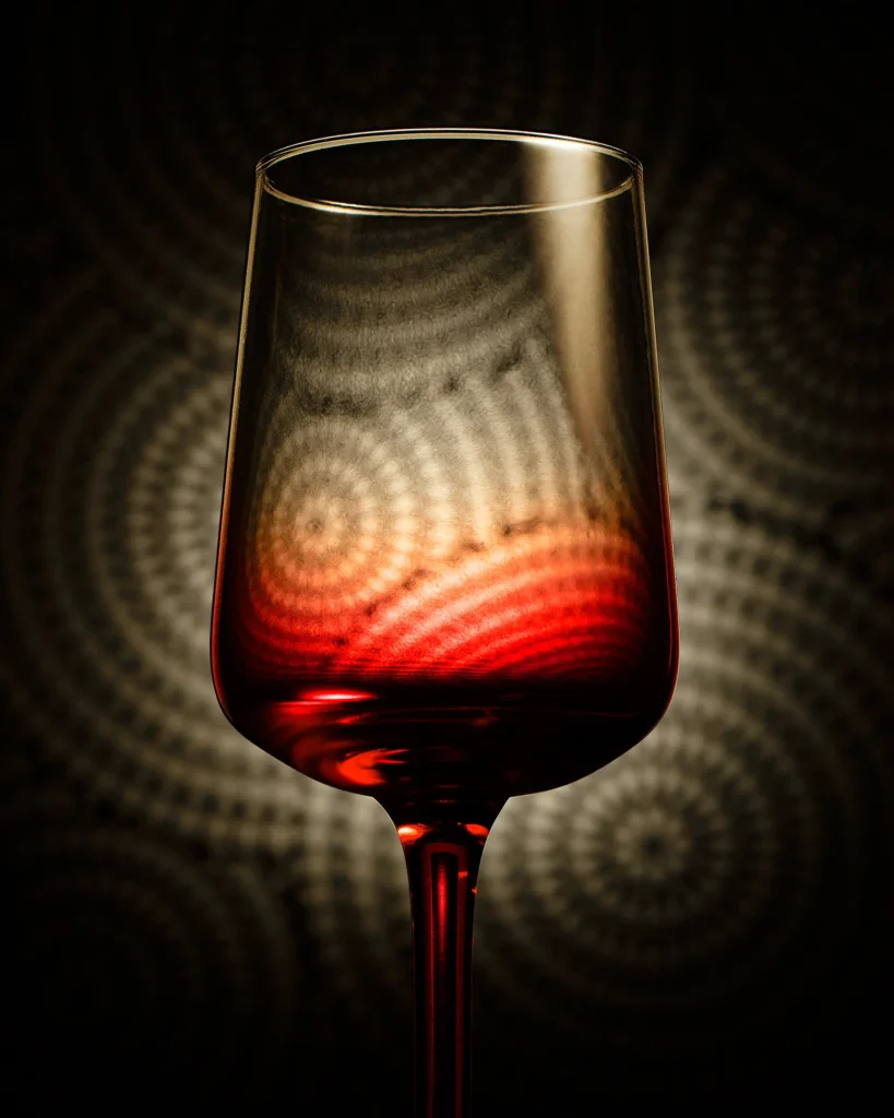 Red wine glass against a warm concentric light pattern