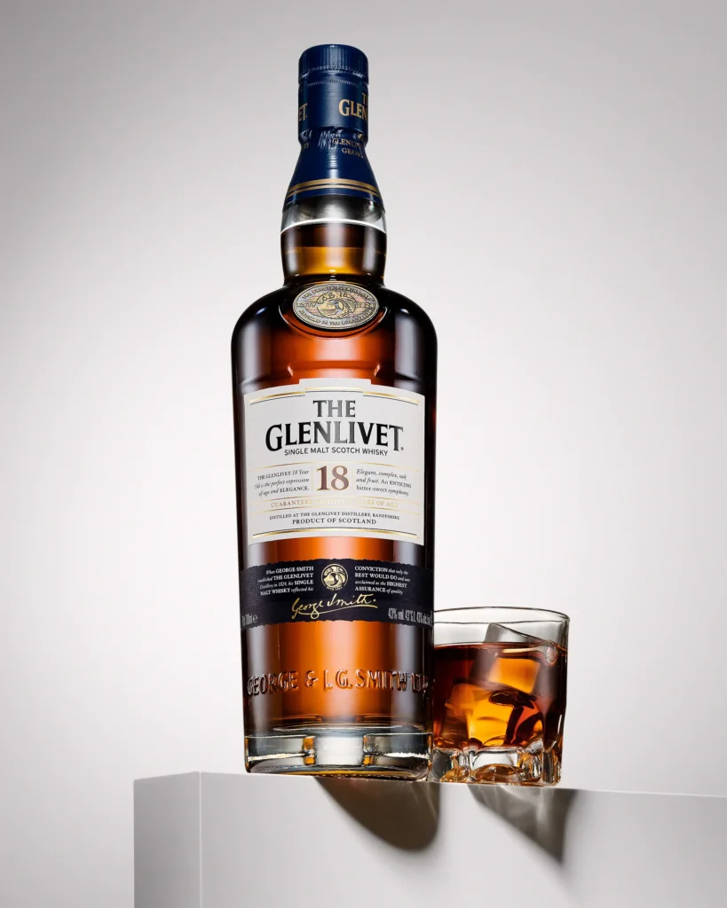 Single malt bottle and tumbler on a white plinth