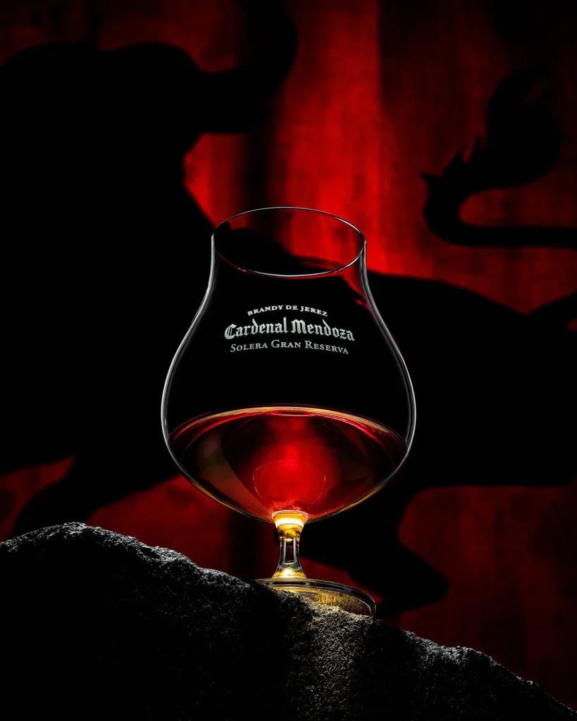Brandy snifter lit red against a smoky dark ground