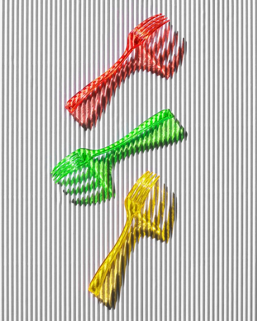 Three coloured plastic forks on a ridged white surface