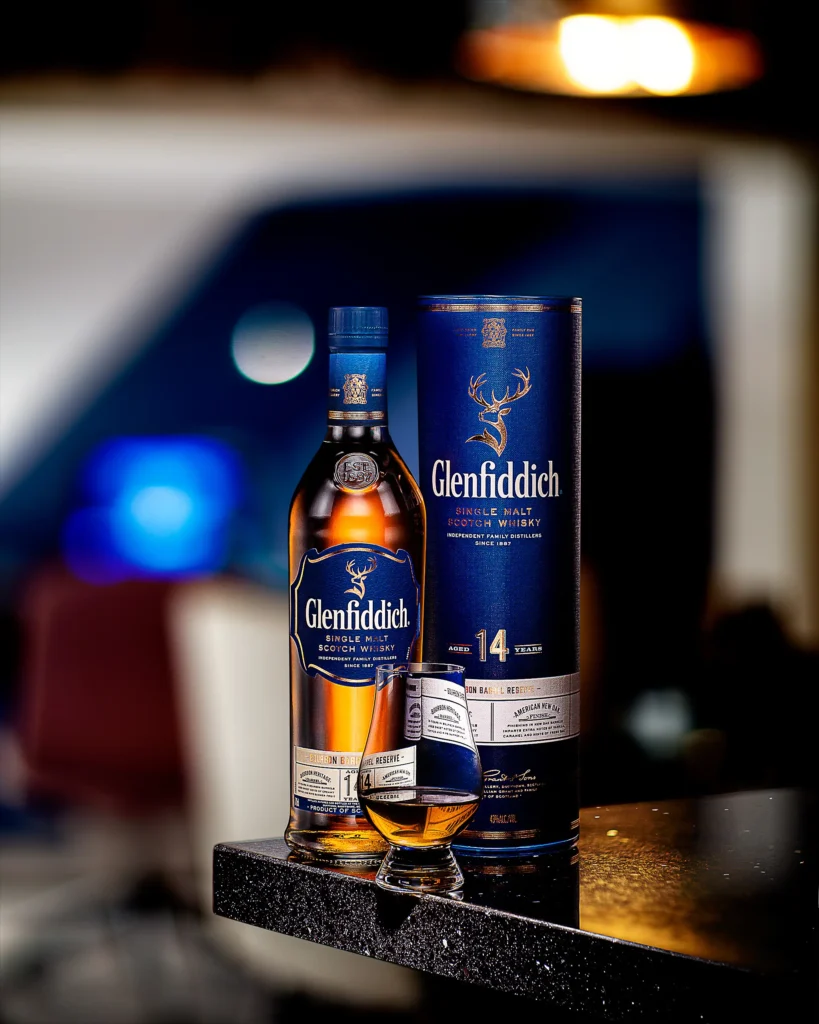 Whisky bottle, tube and glass on a bar counter with warm bokeh