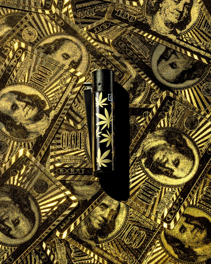 Black lighter with leaf motif on a scatter of gold banknotes