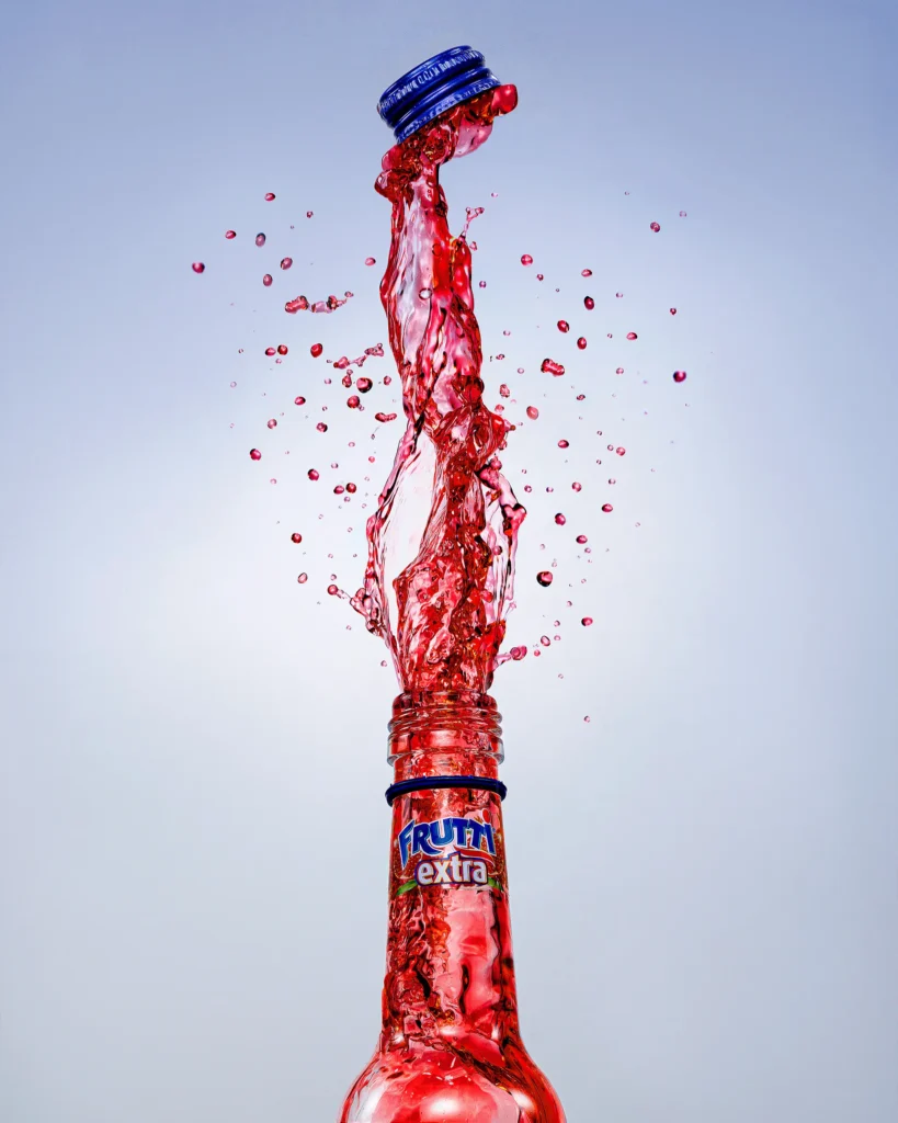 Red drink bursting upward out of a clear bottle