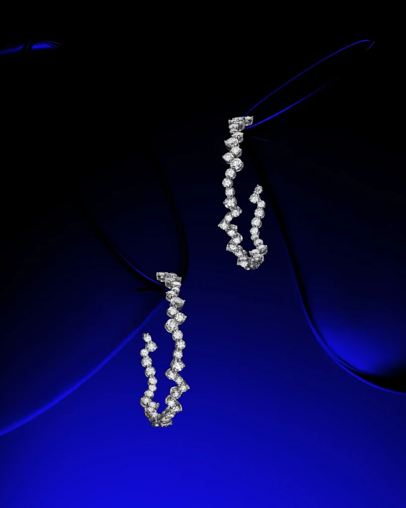 Two diamond necklaces suspended against deep blue