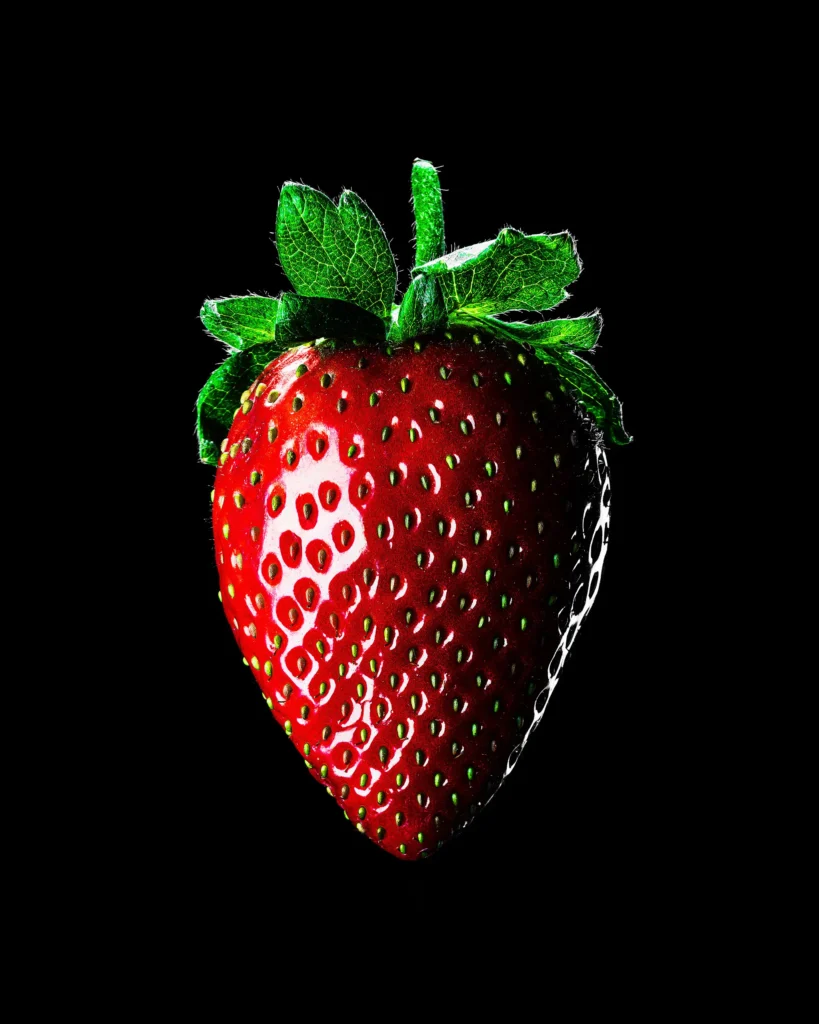 Single strawberry lit against black