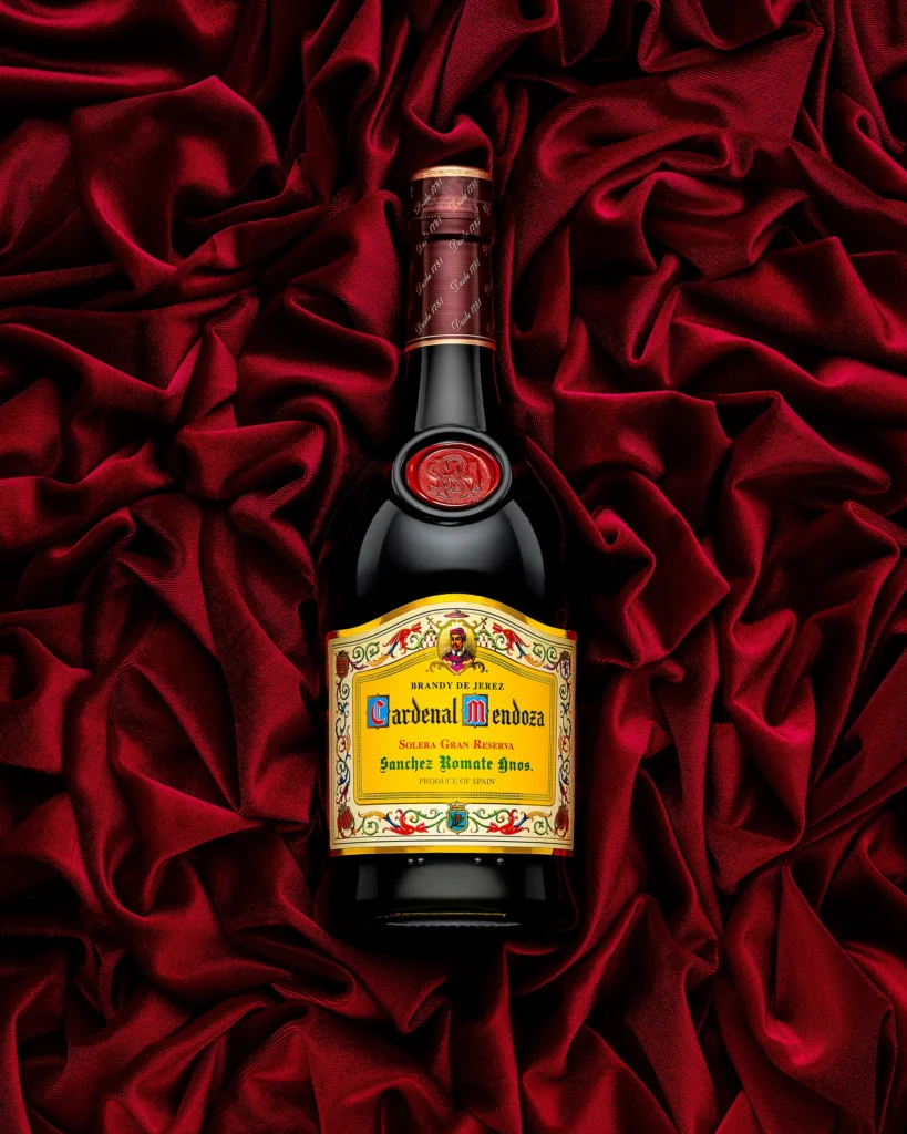 Brandy bottle lying on folds of deep red velvet