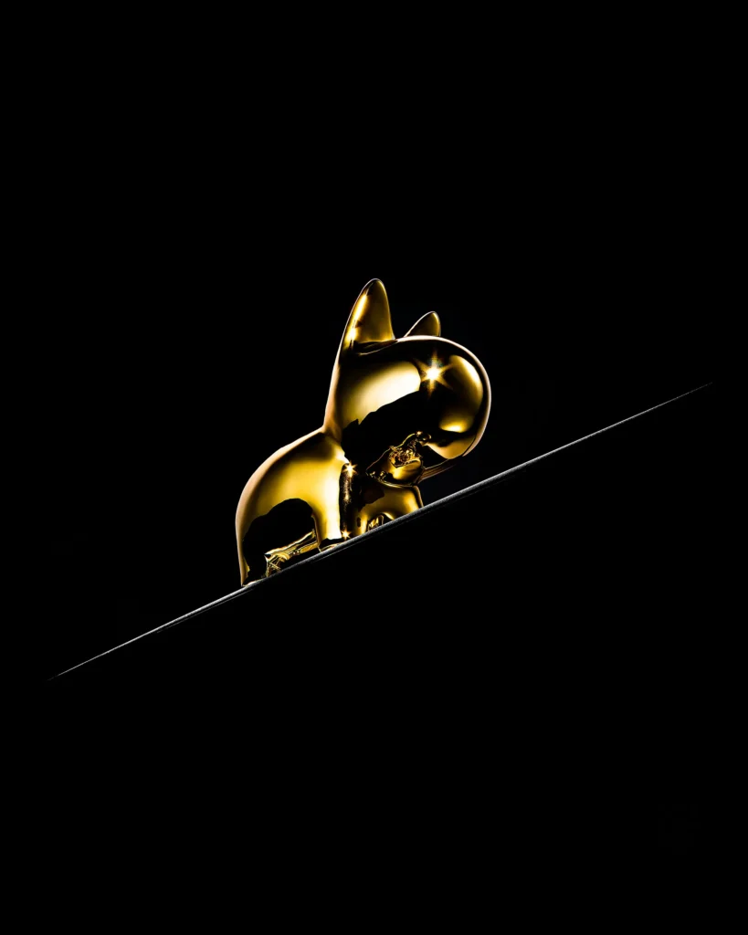 Gold cat figurine perched on a thin lit edge