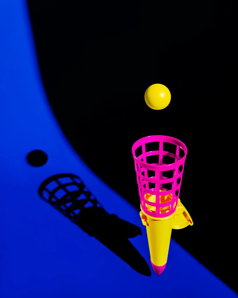 Pink and yellow toy shuttlecock launcher on cobalt
