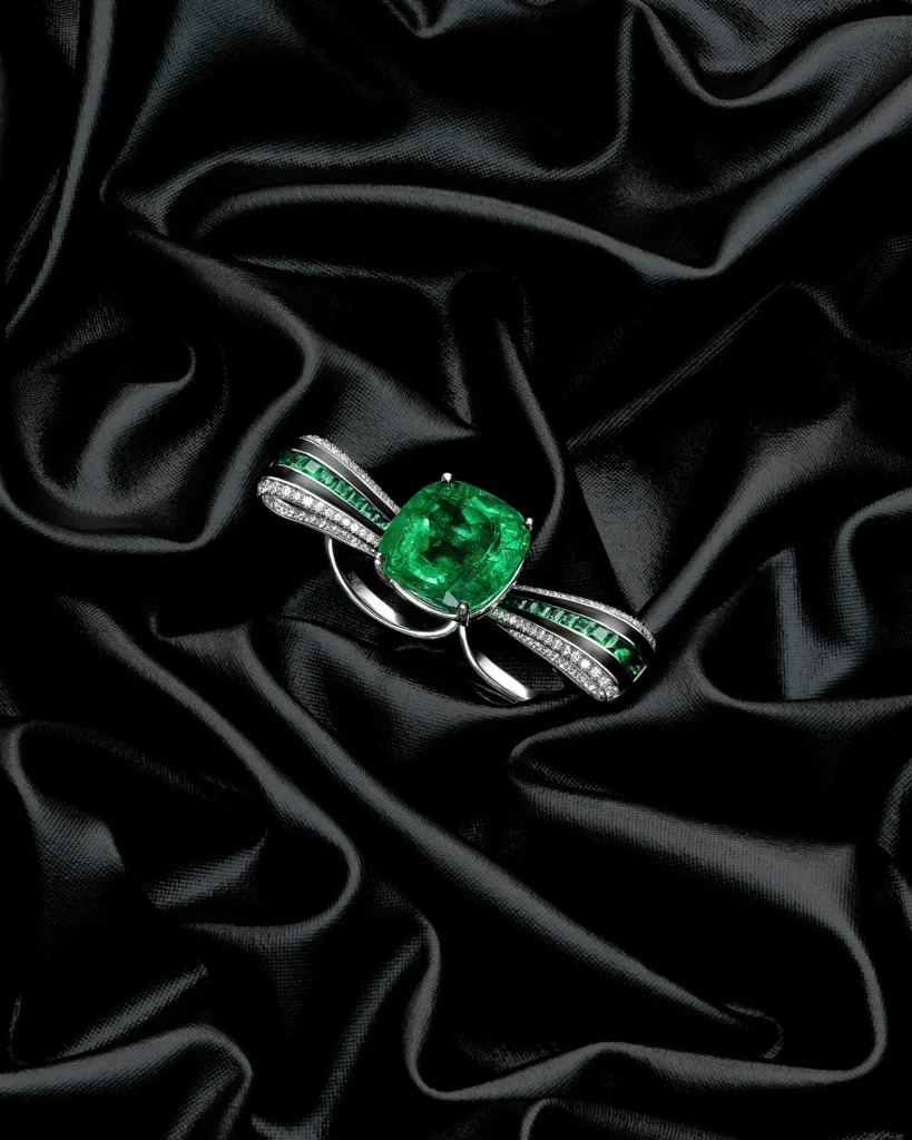 Emerald and diamond ring on black satin folds