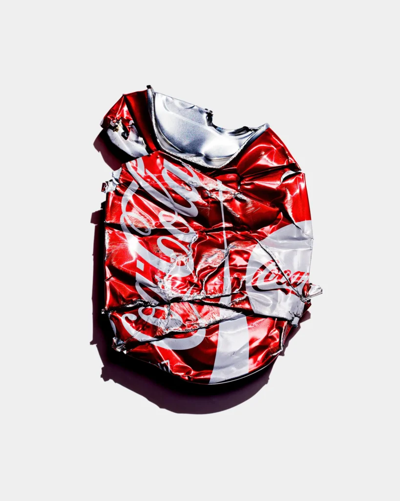 Crushed red drinks can flattened on white