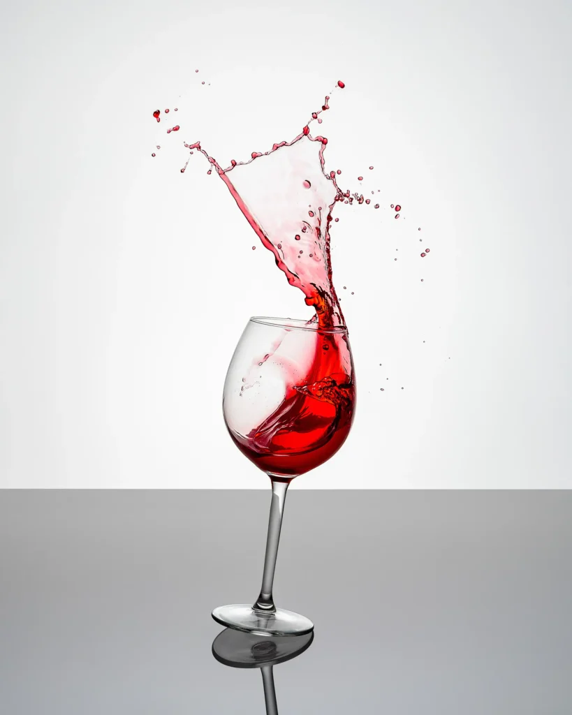 Red wine leaping from a glass on a pale ground