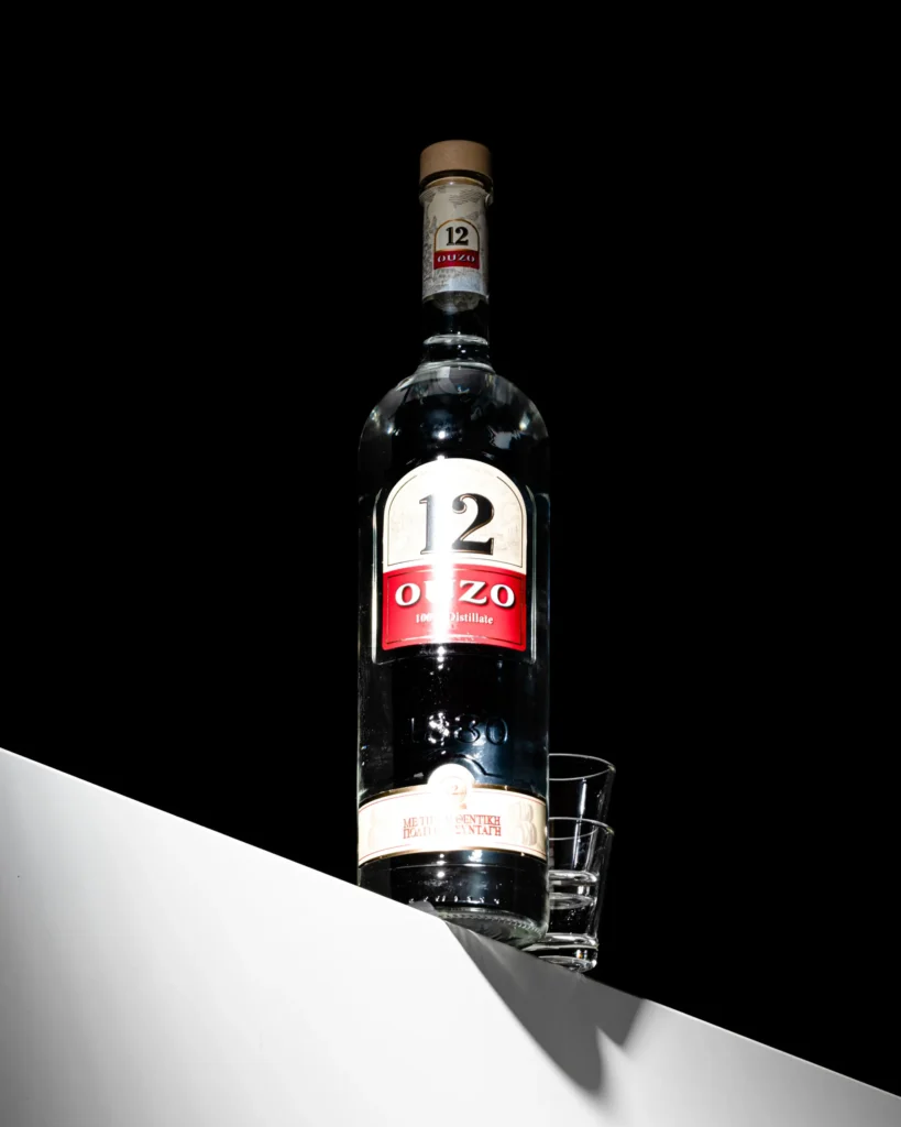 Aniseed spirit bottle and glass on a red and black diagonal (unretouched original)