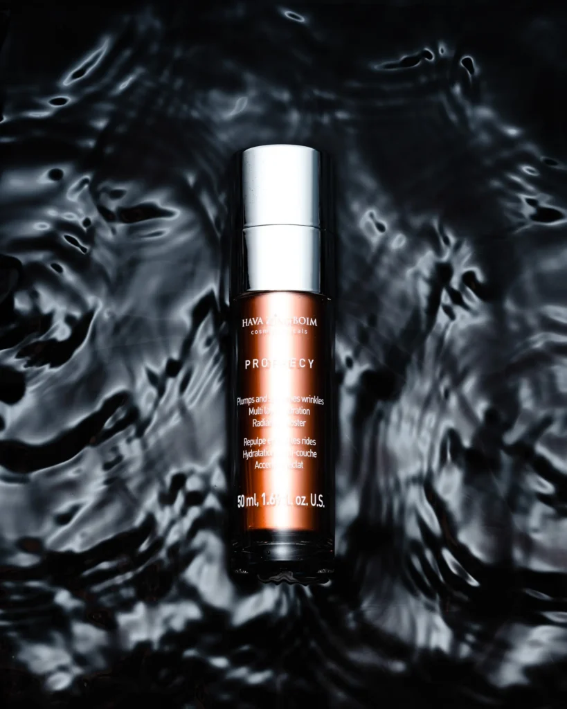 Slim serum bottle standing in dark rippling water (unretouched original)