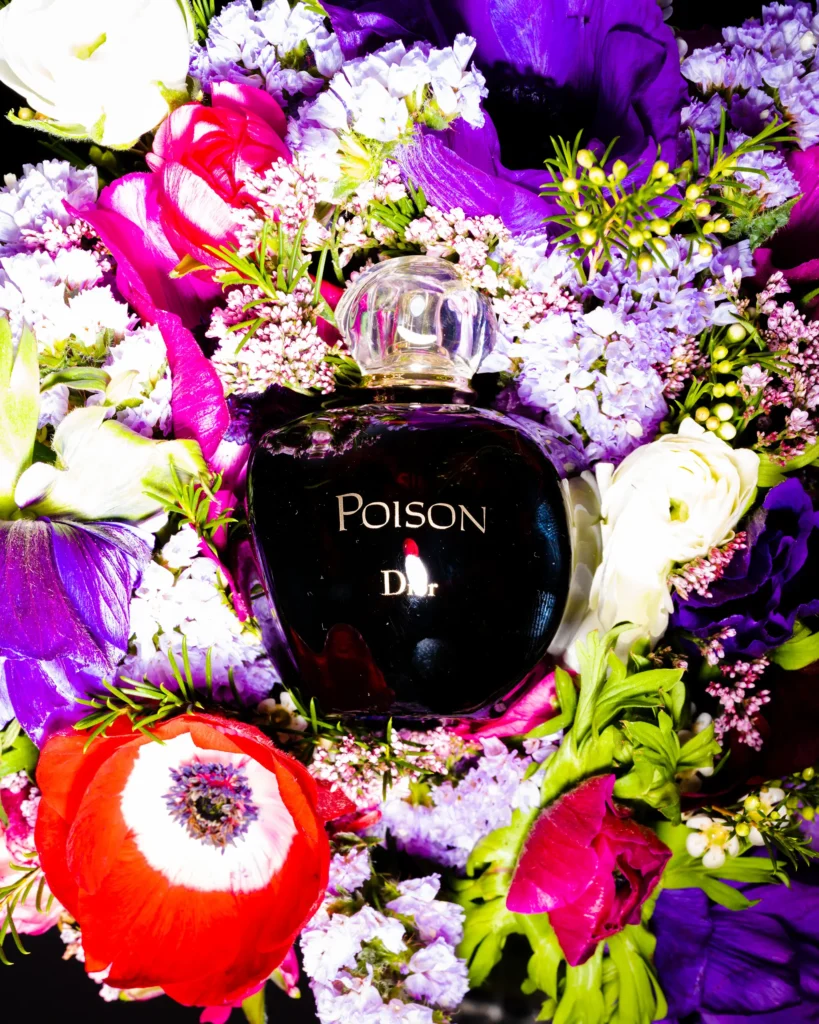 Dark perfume flask set into a bouquet of purple and red flowers (unretouched original)