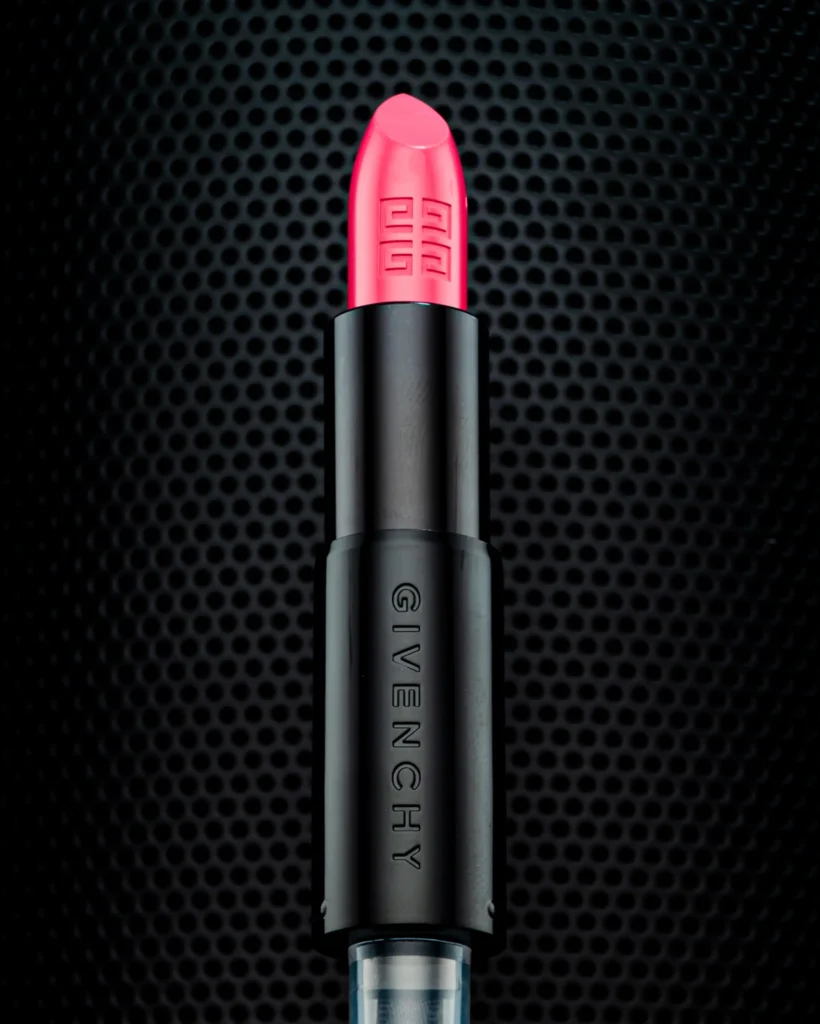Pink lipstick in a black case on a perforated metal grid (unretouched original)