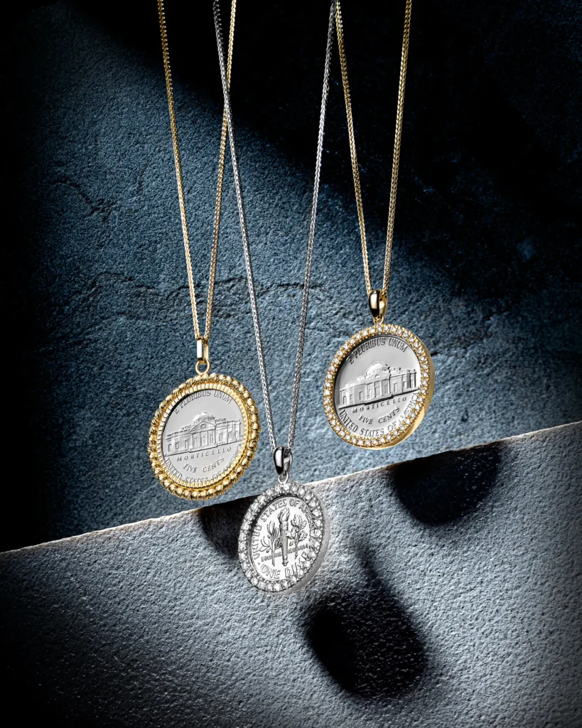 Three medallion pendants on fine chains against grey stone (retouched)