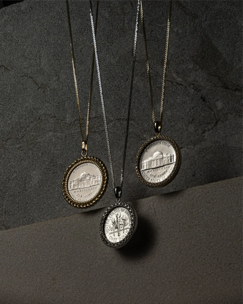 Three medallion pendants on fine chains against grey stone (unretouched original)