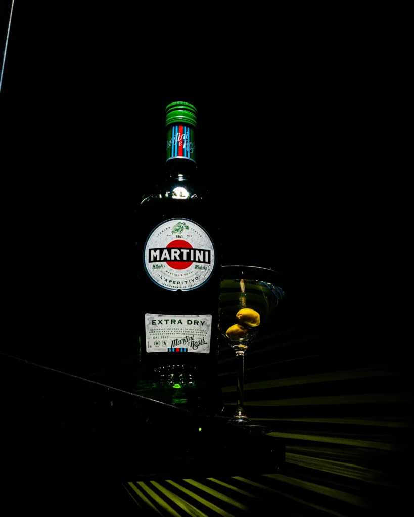 Green vermouth bottle and cocktail glass over a lit palm frond (unretouched original)