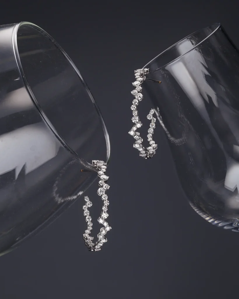 Two diamond hoop earrings against deep blue (unretouched original)