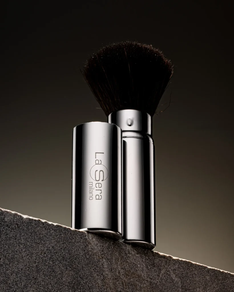 Powder brush and silver handle balanced on a dark stone edge (unretouched original)