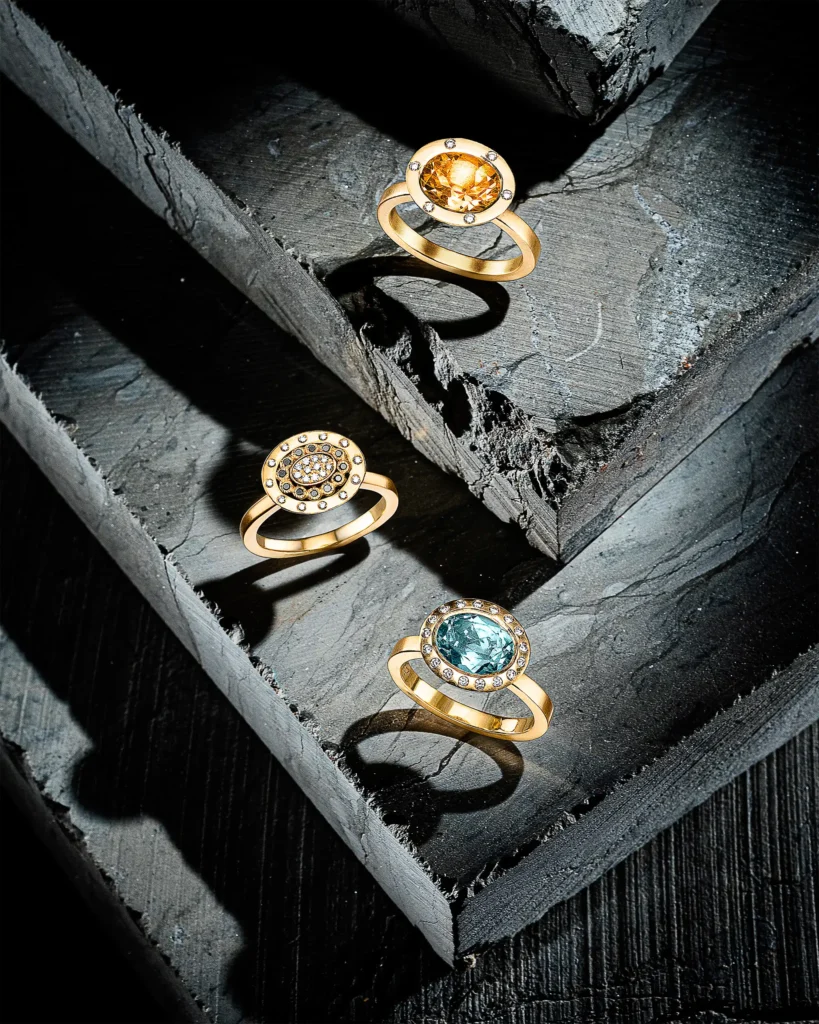 Three gold gemstone rings on stepped grey slate (retouched)