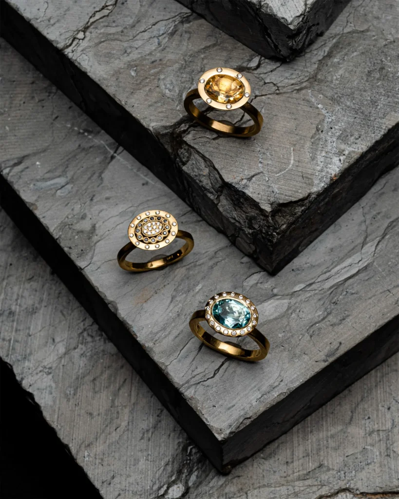Three gold gemstone rings on stepped grey slate (unretouched original)